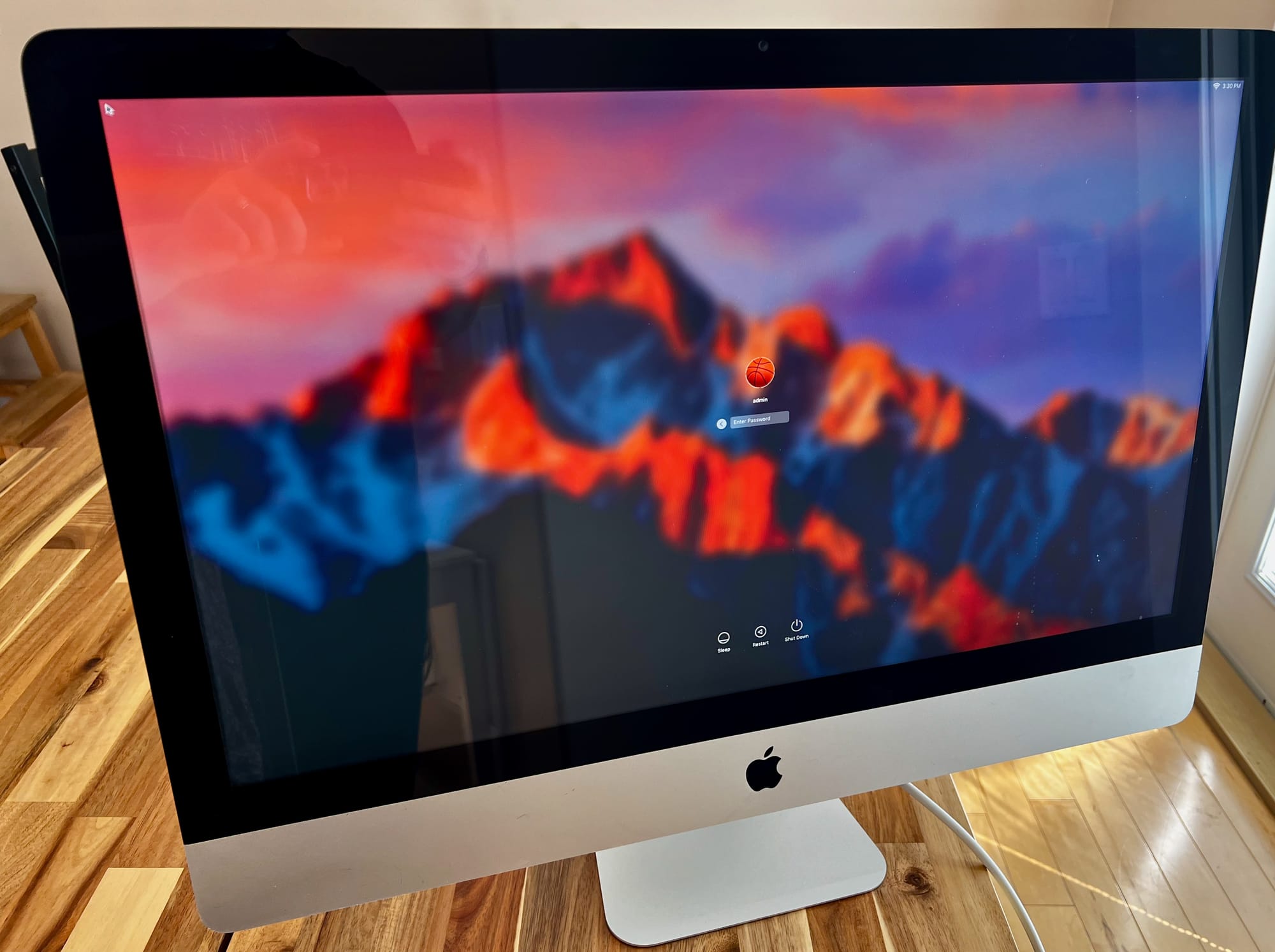 An iMac on a table with a login screen for an admin account.